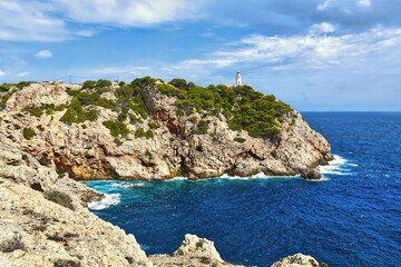 A sea with waves hitting the rocky shore and blue summer skies