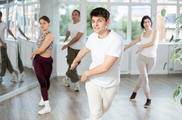 Fototapeta premium Smiling people practicing vigorous lindy hop movements in dance class