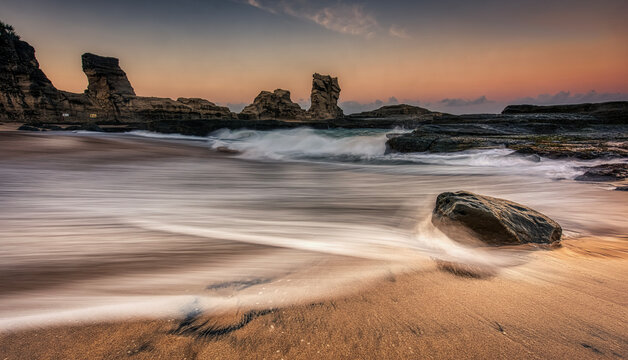 Beautiful sunrise beach showing water flow path foreground around the rocks with golden hours sky background