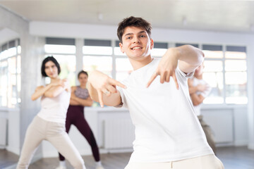Fototapeta premium Expressive Hispanic guy honing hip-hop dance moves in mirrored choreographic studio setting during group training..