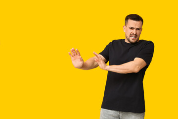 Handsome ashamed young man on yellow background