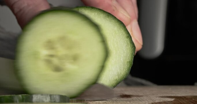 Macro close up of cucumber being sliced on chopping board for cooking, food culinary preparation