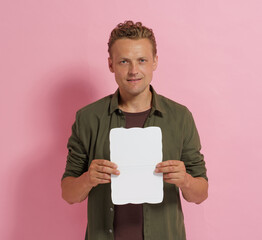 A man is holding a white card in his hand. The card is rectangular and has a white background. The man is smiling and he is happy