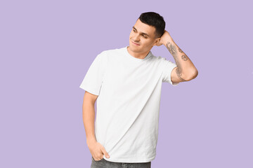 Handsome ashamed young man on lilac background