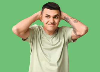 Handsome ashamed young man on green background