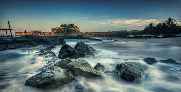 Beautiful sunrise beach showing water flow path foreground around the rocks with blue hours sky