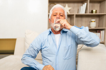 Senior man holding glass drinking fresh water at home. Mature old senior thirsty grandfather takes care of his health. Healthcare water balance. Elderly healthy lifestyle