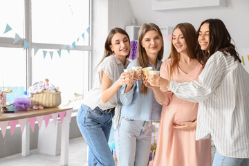 Young pregnant woman with her friends drinking at baby shower party