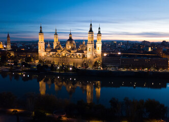Scenic twilight view from drone of illuminated Basilica of Our Lady of Pillar on bank of Ebro river...