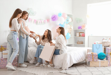 Obraz na płótnie Canvas Young pregnant woman receiving gifts from her friends at baby shower party in bedroom