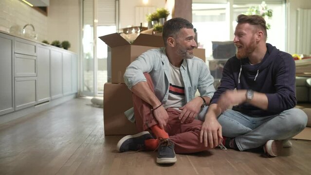 Male gay couple making plans in new home after moving in