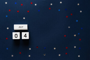 american independence day, top view on wooden cubes calendar 4th of july on blue background with confetti stars	