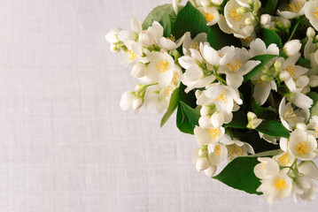 Bouquet of fresh delicate spring jasmine flowers on a linen tablecloth on the table. Top view,...