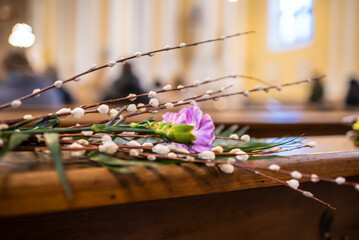 Willow branches, lilac carnations, palm leaf on a wooden table in a church. Palm Sunday.