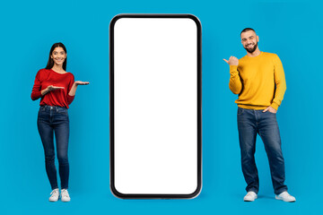 Happy man and woman pointing at blank smartphone screen