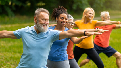 Group of diverse seniors led by instructor practicing warrior yoga pose outdoors