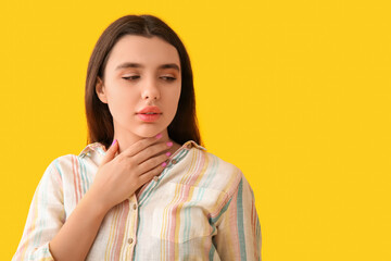 Young woman with thyroid gland problem on yellow background