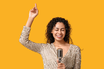 Beautiful young happy African-American female singer with microphone pointing at something on...
