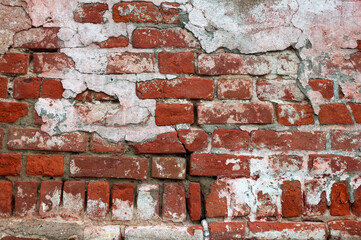 Texture of old weathered red brick wall with cracks and remains of plaster