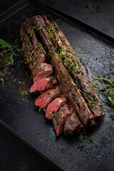 Traditionally roasted saddle of venison with fillet pieces and herbs served as close-up on a rustic...