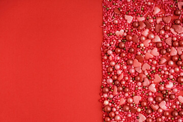 Sweet colorful sprinkles on red background