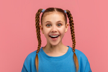 Excited girl with braided pigtails on pink