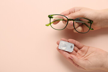 Female hand with contact lens and eyeglasses on beige background