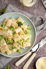 Plate of tasty pasta with broccoli on grey background