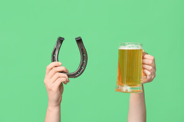 Hands with beer and horseshoe on green background. St. Patrick's Day celebration