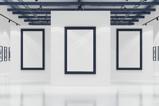 A minimalist white art gallery showcasing empty blank mock-up posters within deep navy blue frames. 