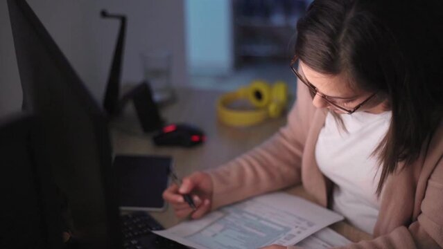 A woman sitting by computer and working on personal finance at home

