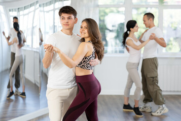 Couple of young guy and young woman dancing waltz in studio