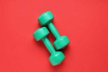 Pair of green dumbbells on red background