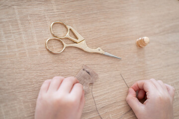 Close-up child's hands carefully stitching doll's dress, highlighting fine motor skills and...