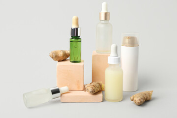 Composition with bottles of cosmetic products, ginger and plaster podiums on light background