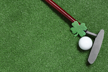Golf club, ball and clover on green grass background. St. Patrick's Day celebration