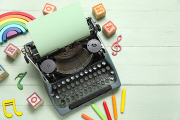 Vintage typewriter with paper and toys on green background