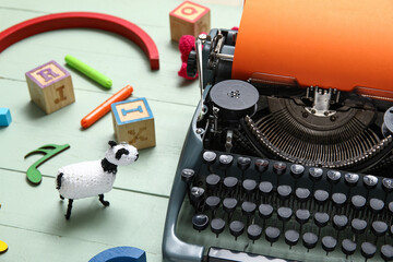 Vintage typewriter with orange paper and knitted toys on green background