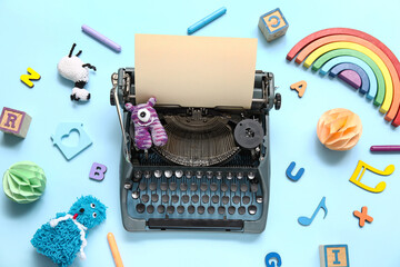 Vintage typewriter and knitted toys on blue background