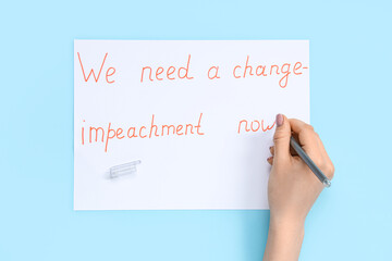 Woman writing text WE NEED A CHANGE - IMPEACHMENT NOW on picket poster against blue background
