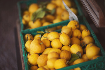 Natural lemons in crates on supermarket. sale, shopping, vitamin c and healthy food concept - ripe lemons in box with nameplate at grocery market. 