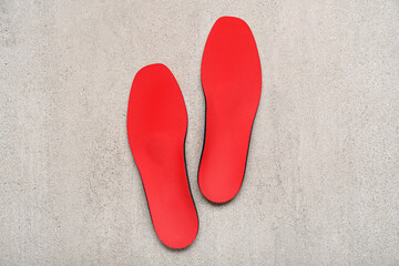 Red orthopedic insoles on grey grunge background