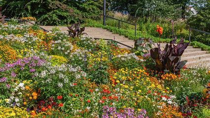 Ein buntes Blumenbeet im Park Planten un Blomen (Pflanzen und Blumen) in Hamburg, dahinter eine Treppe. - obrazy, fototapety, plakaty
