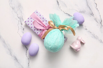 Painted and chocolate Easter eggs wrapped in paper with gift box on white grunge background