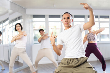 Guy, together with dance youth group, rehearses performance, works out succession of events movements execution of dancing show, modern energetic dances.