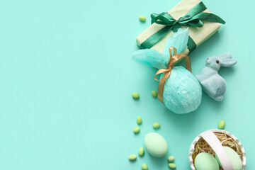 Ceramic basket with Easter eggs, toy bunny and gift box on turquoise background