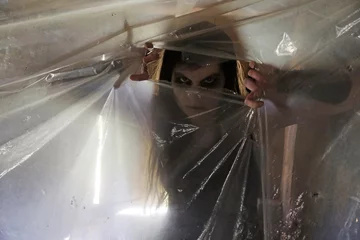 Foto op Plexiglas Eine junge Frau als böses Wesen, Geist, Untote oder Zombie hinter einer Plastikfolie © Astrid Gast