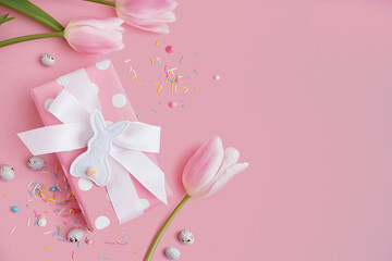 Gift box with tulip flowers and Easter toy bunny on pink background
