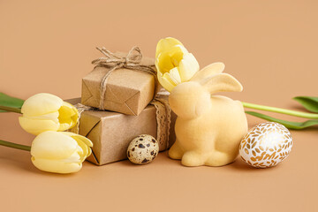 Easter eggs with gift boxes, toy bunny and tulip flowers on brown background