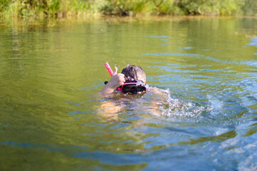 Child bathing in pink mask in water in summer. High quality photo